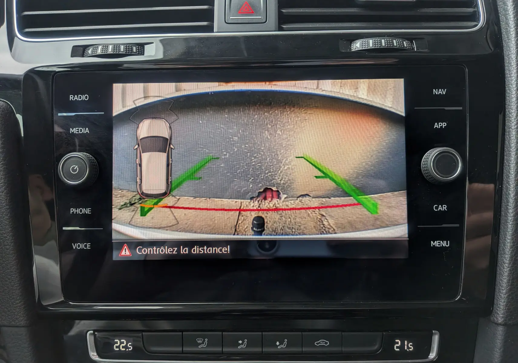 Affichage de la caméra de recul sur l'écran central de la Volkswagen Golf VII blanche, avec guidage vert et rouge et avertissement de distance.