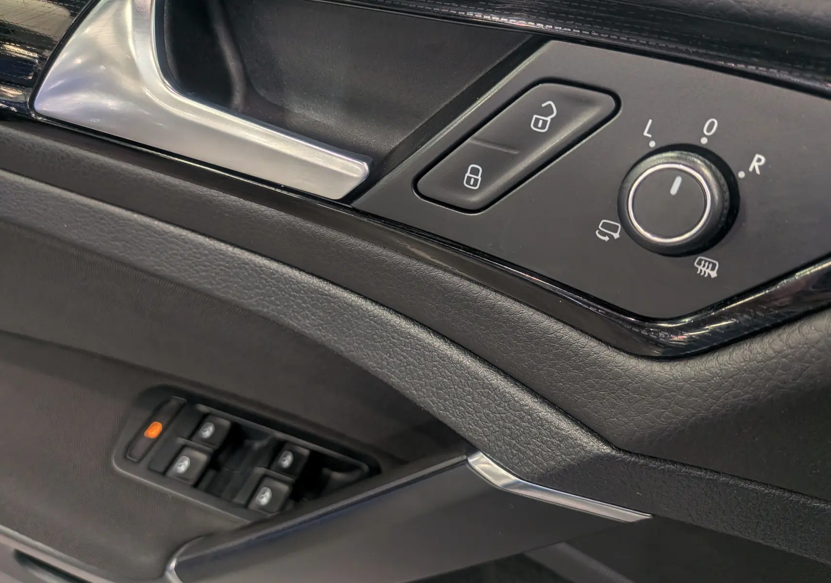 Détail de la porte côté conducteur d'une Volkswagen Golf VII TSI blanche, avec commandes des vitres et réglages des rétroviseurs.