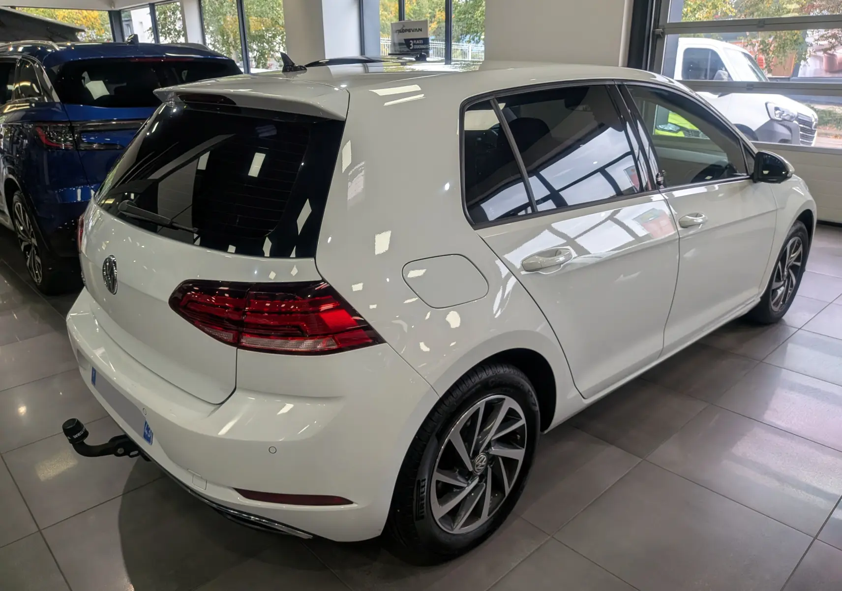 Volkswagen Golf VII TSI 125 ch Sound blanc pur vue 3/4 arrière droit avec attelage en intérieur showroom.