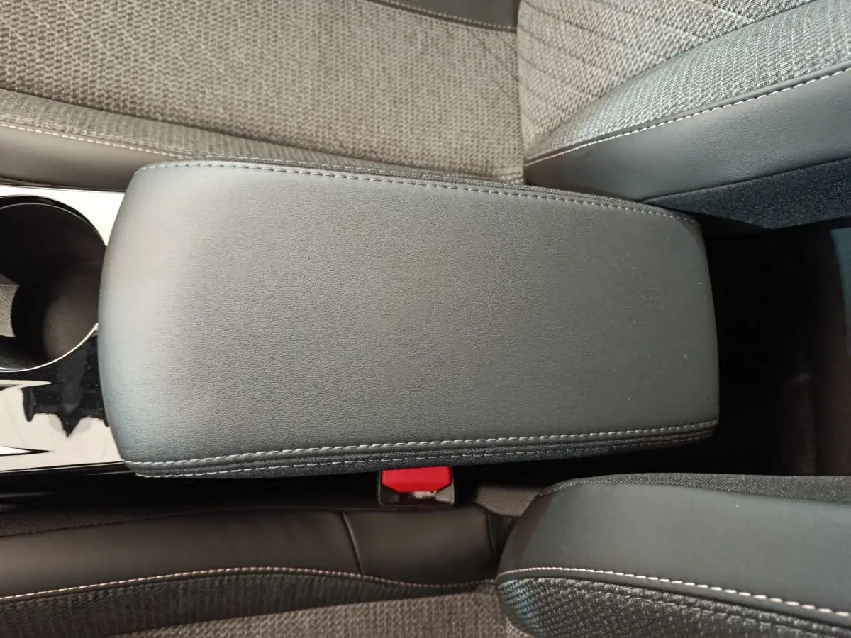 Accoudoir central noir en cuir et tissu gris clair dans l'habitacle d'une Peugeot 208 PureTech 100 S&S Allure 2025.