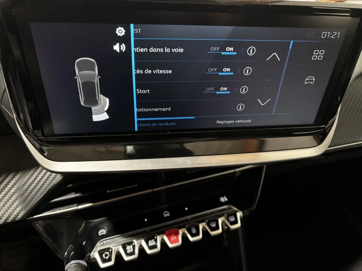 Gros plan sur l'écran tactile central et la console de commandes de la Peugeot 208 hybride, intérieur noir avec détails carbone.