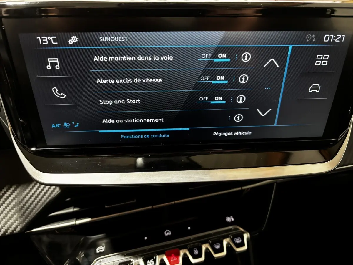 Écran tactile central de la Peugeot 208 Hybrid 110, affichant les réglages d’aide à la conduite, intérieur noir.