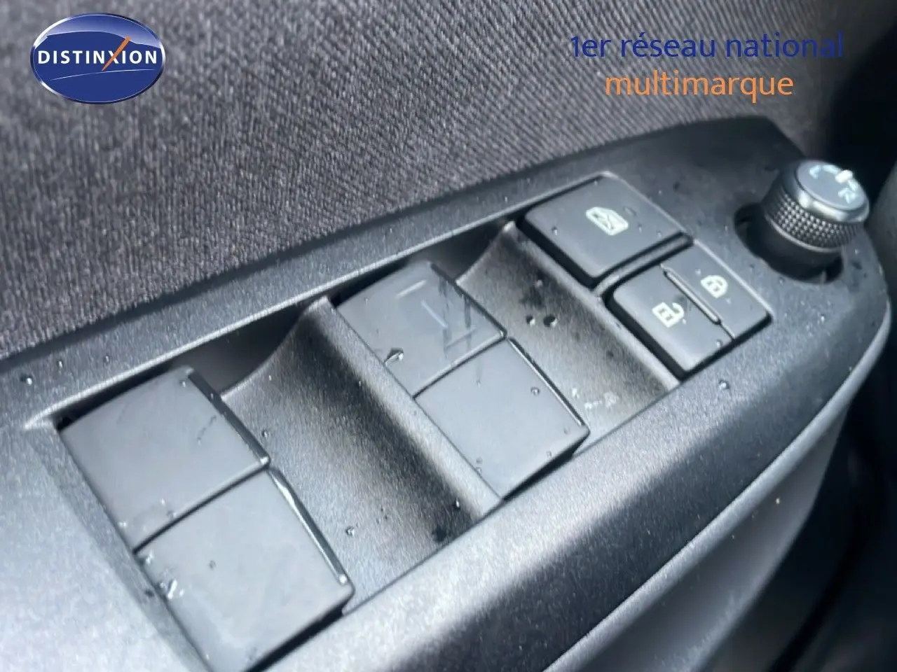 Gros plan sur les commandes de lève-vitres et rétroviseurs côté conducteur d'une Toyota Yaris Cross blanche.