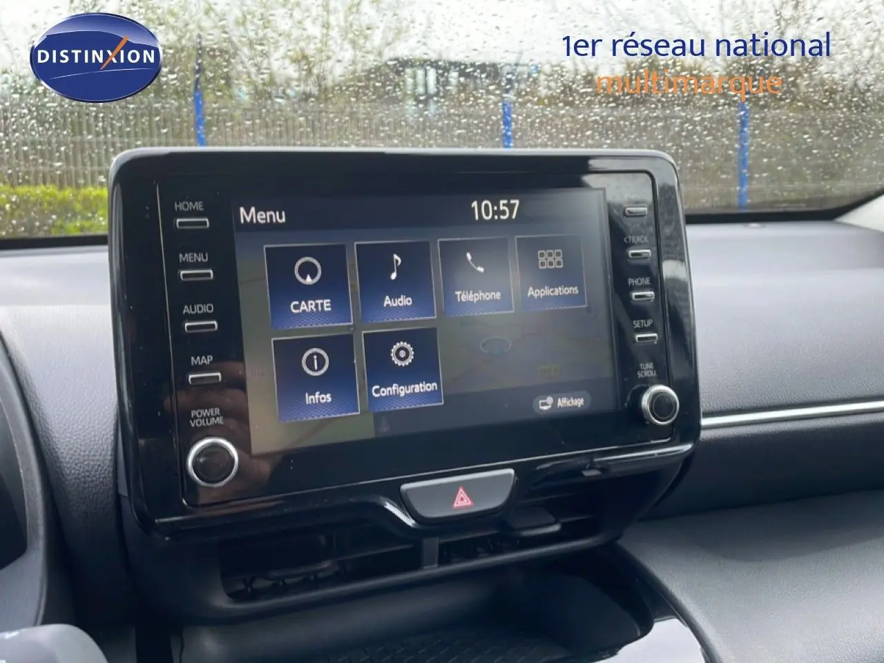 Écran tactile central de la Toyota Yaris Cross Hybrid blanc, vue intérieure du tableau de bord sous la pluie.