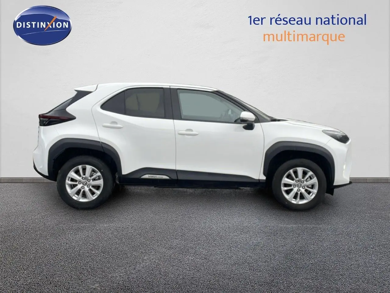 Profil droit d'une Toyota Yaris Cross hybride blanche 2024 avec protections noires sur les passages de roues.