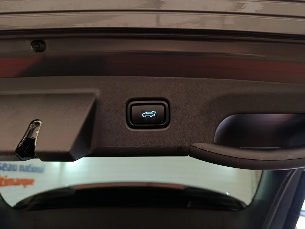 Bouton d'ouverture électrique du coffre vu de l'intérieur du hayon d'un Hyundai Tucson gris foncé 2025.
