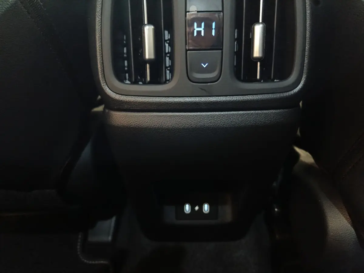 Vue rapprochée de la console arrière du Hyundai Tucson 2025 gris foncé avec commandes de ventilation et ports USB éclairés.