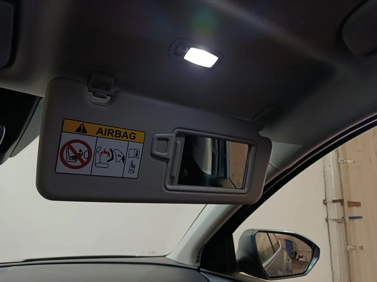 Détail intérieur du pare-soleil côté conducteur avec miroir et avertissement airbag dans un Hyundai Tucson gris foncé.