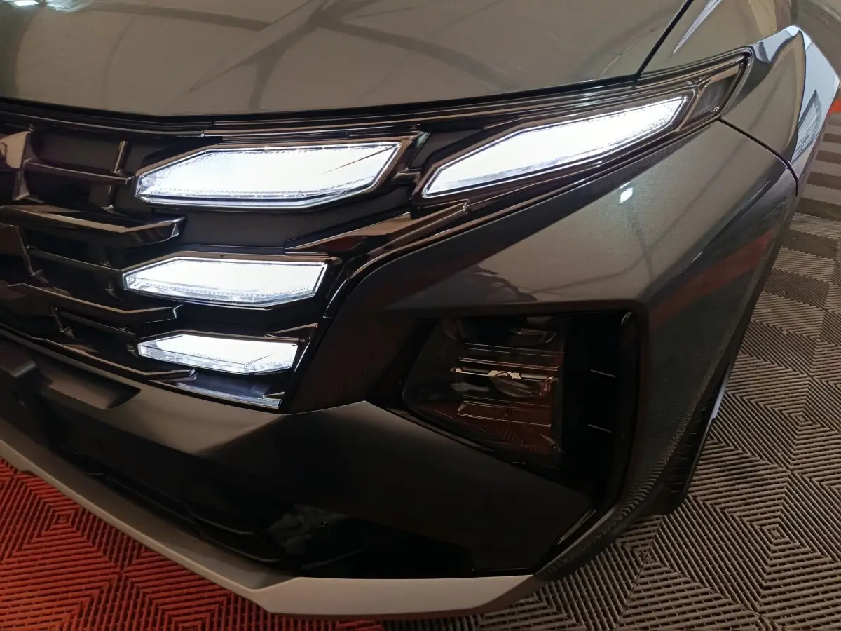 Gros plan sur l'avant droit gris foncé du Hyundai Tucson 2025 avec phares LED et calandre distinctive.