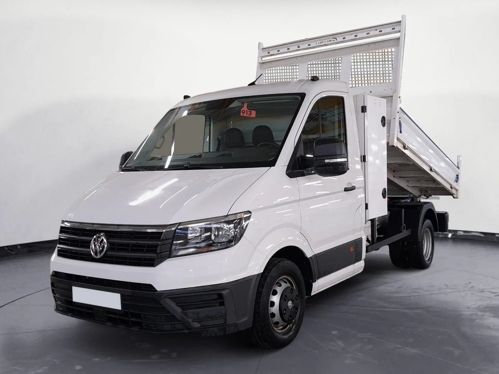Vue 3/4 avant d’un Volkswagen Crafter blanc avec benne relevée, coffre latéral et roues jumelées arrière.