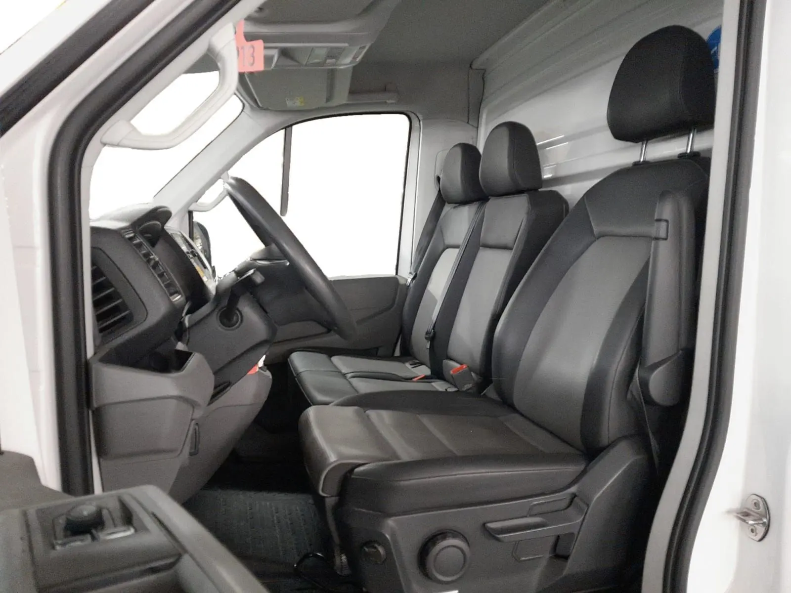 Vue intérieure côté gauche du Volkswagen Crafter Chassis Cabine blanc 2021, montrant les sièges en cuir noir et le tableau de bord.
