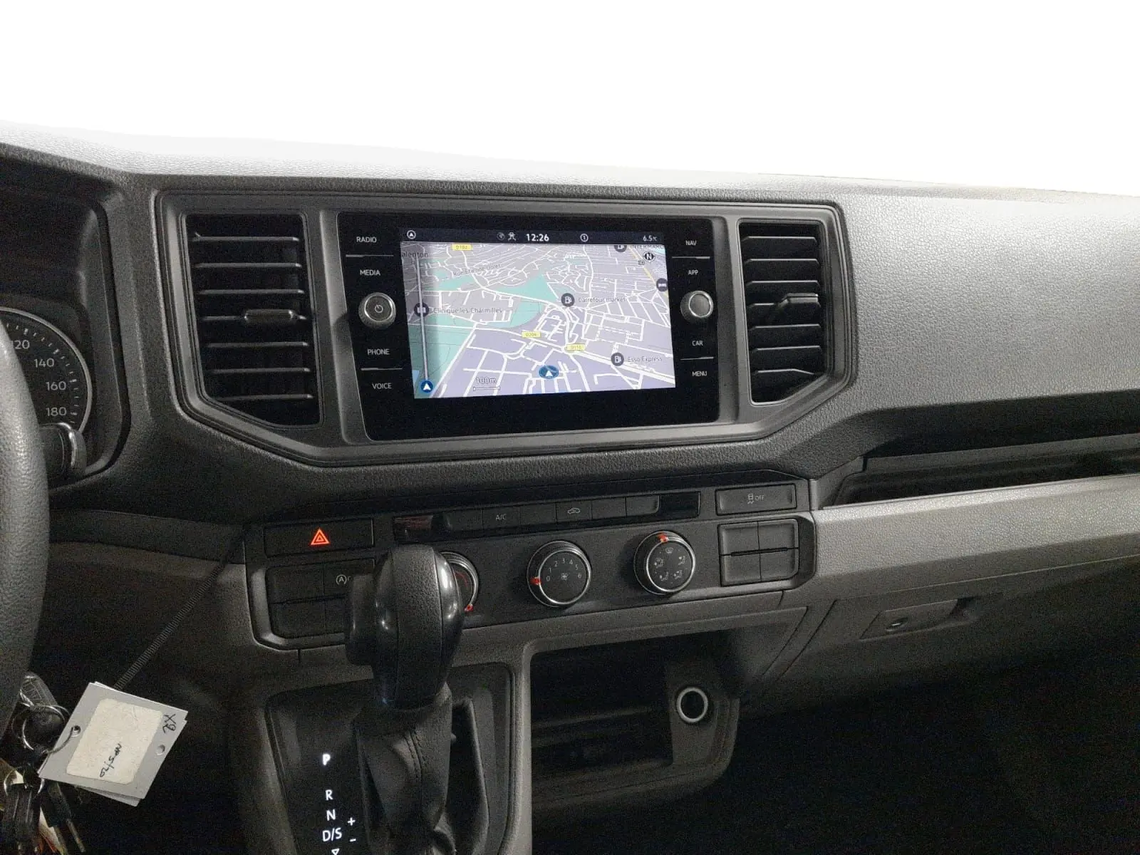 Vue intérieure du tableau de bord du Volkswagen Crafter blanc, avec écran tactile central affichant une carte de navigation.