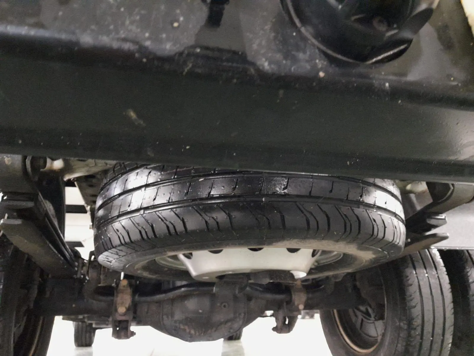 Gros plan sous le châssis du Volkswagen Crafter blanc, montrant la roue de secours et les suspensions arrière.