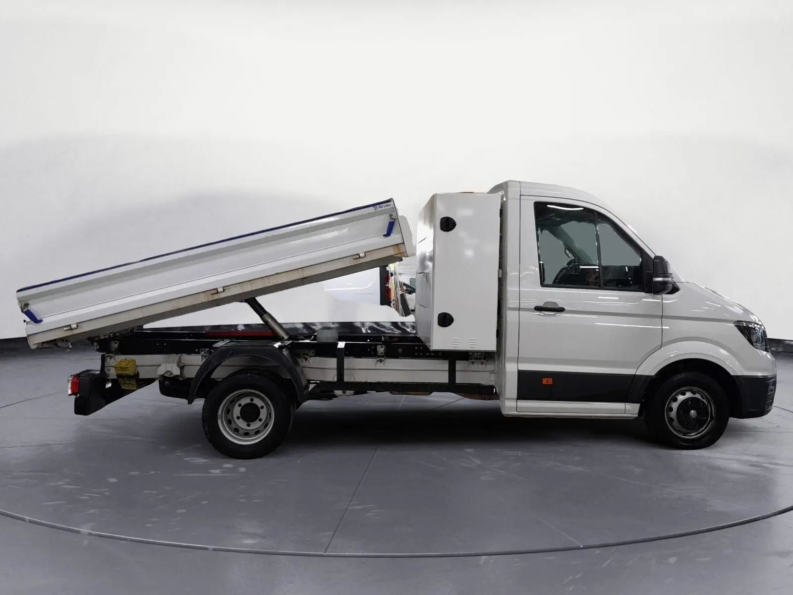 Vue latérale droite d’un Volkswagen Crafter blanc 2021 avec benne relevée et coffre arrière, roues jumelées visibles.