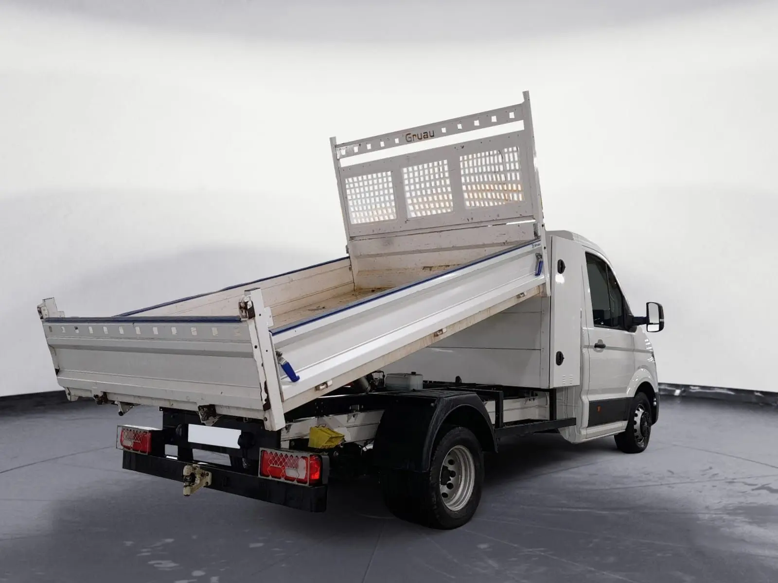 Volkswagen Crafter blanc en benne basculante vu en 3/4 arrière droit avec coffre et roues jumelées.