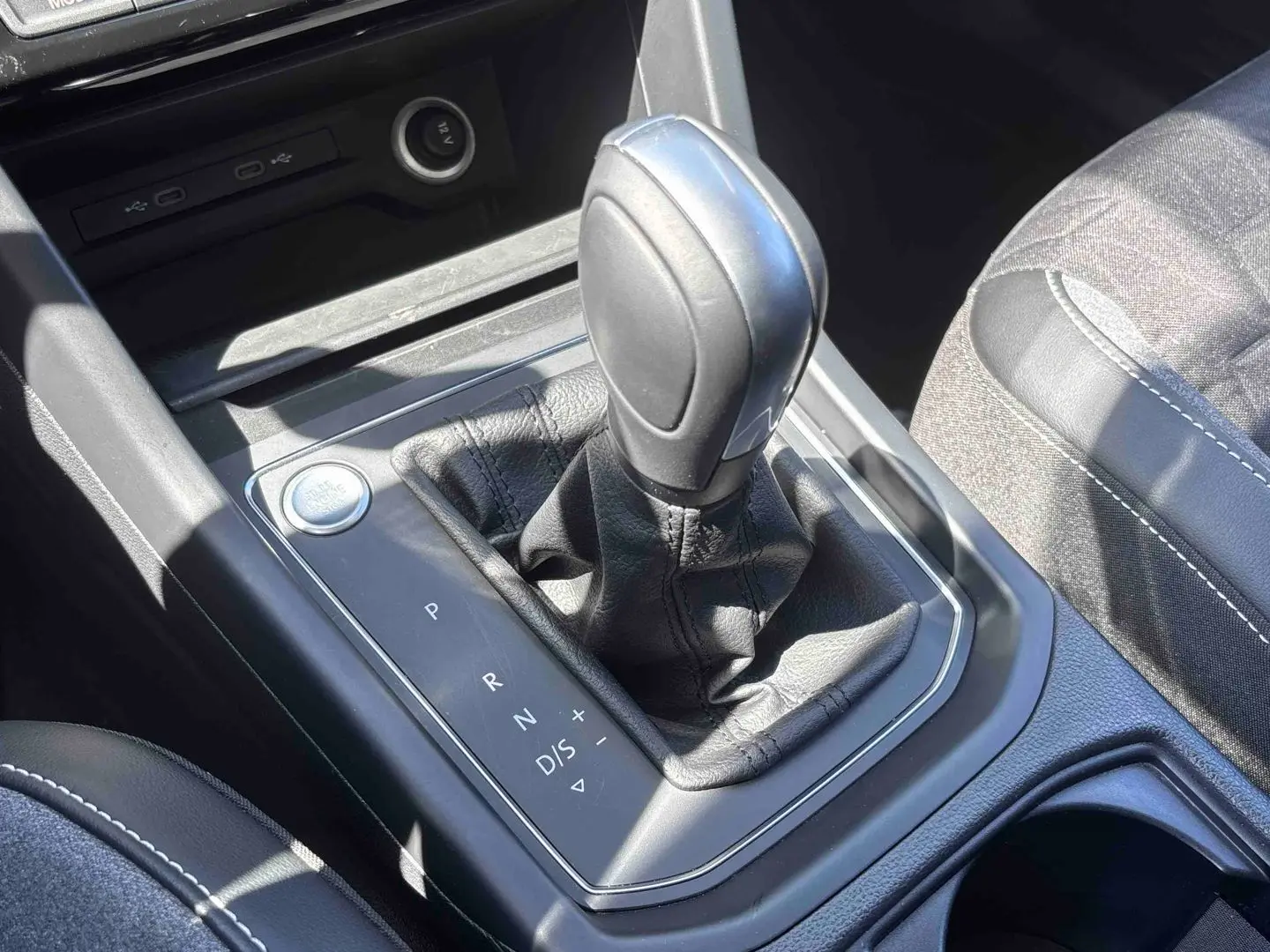 Gros plan sur la commande de boîte automatique DSG7 et le bouton Start/Stop du Volkswagen Touran blanc, intérieur noir.