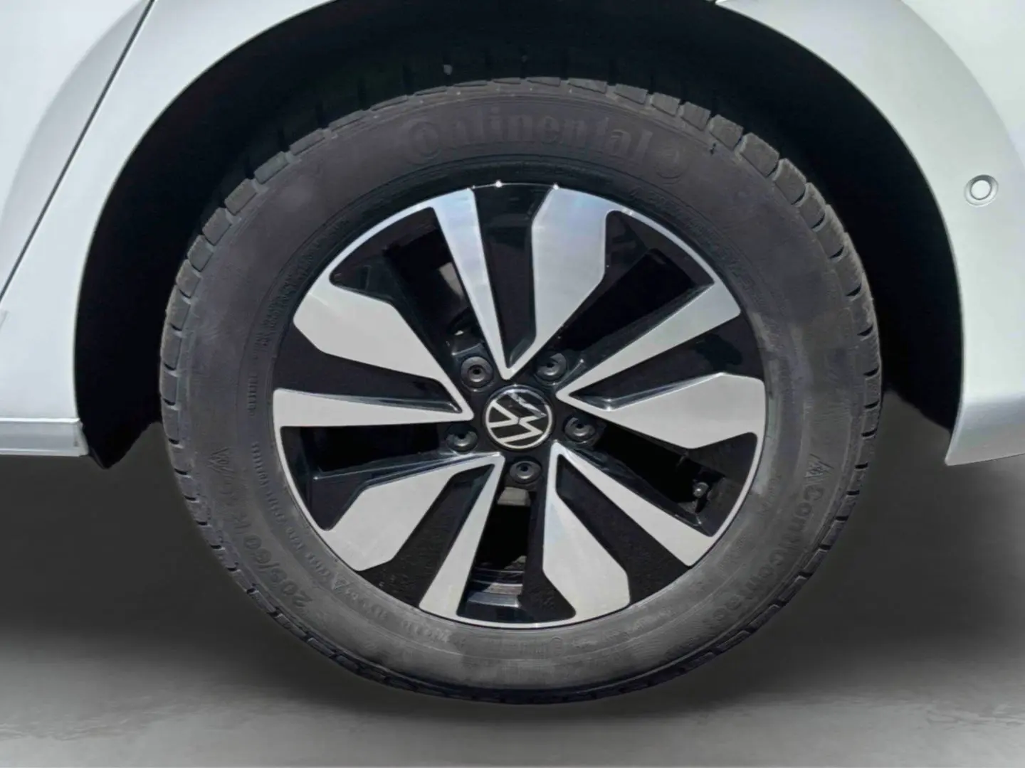 Gros plan sur la jante en alliage bicolore noire et argentée du côté arrière droit d’un Volkswagen Touran blanc.