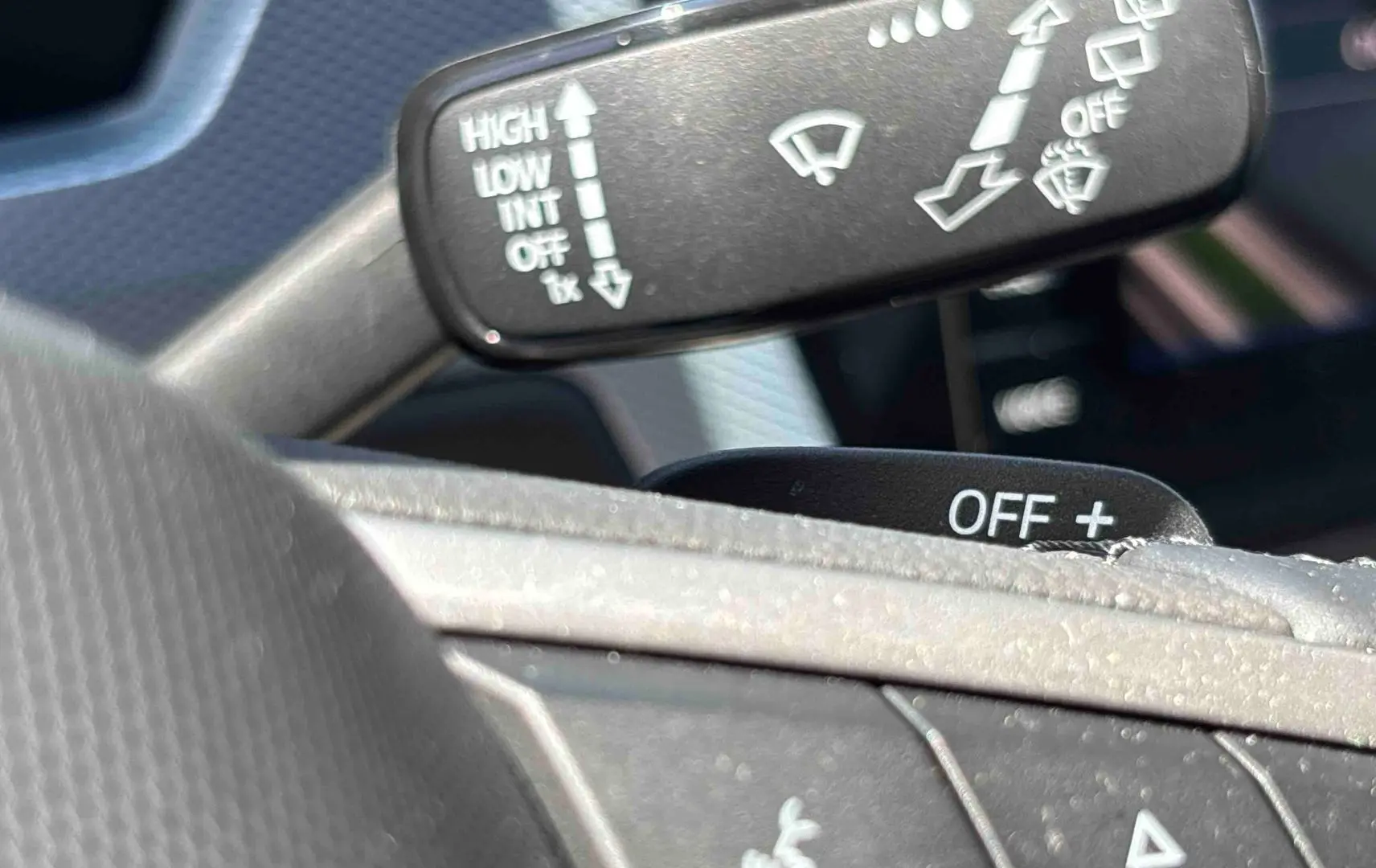 Gros plan sur les commandes de lève-glace et essuie-glace au volant d’un Volkswagen Touran blanc 2025.