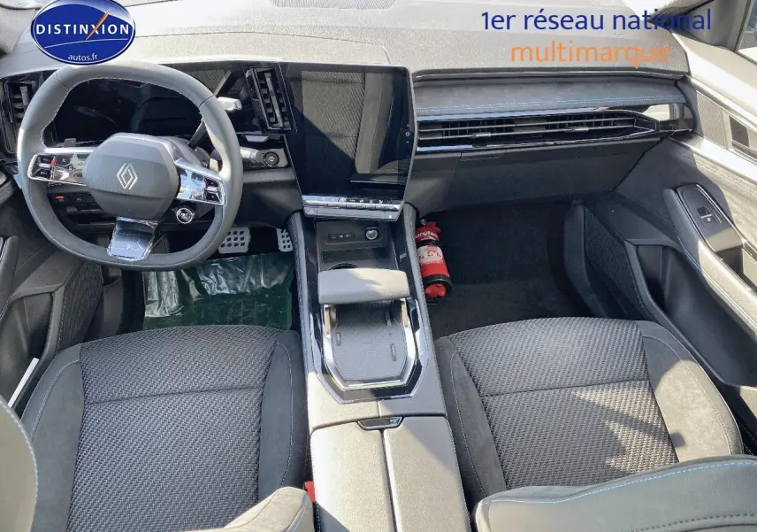 Intérieur avant du Renault Austral 2025, sièges noirs avec surpiqûres bleues et console centrale moderne avec écran tactile.