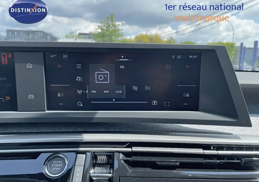 Vue rapprochée de l'écran tactile et console centrale du Peugeot 3008 Hybrid 2025 en bleu Ingaro Metal, avec bouton start/stop visible.