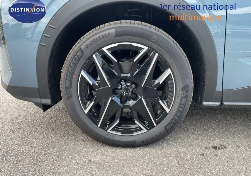 Gros plan sur la roue avant gauche du Peugeot 3008 Hybrid bleu Ingara Metal avec jante noire et argentée au design moderne.