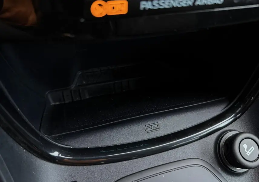 Gros plan sur la console centrale noire du Ford Puma 2024, montrant le chargeur smartphone à induction et allume-cigare.
