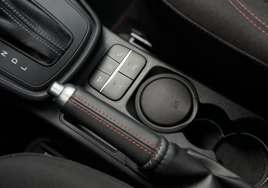 Gros plan intérieur sur le frein à main cuir noir avec surpiqûres rouges du Ford Puma Ecoboost 2024 gris magnétique.