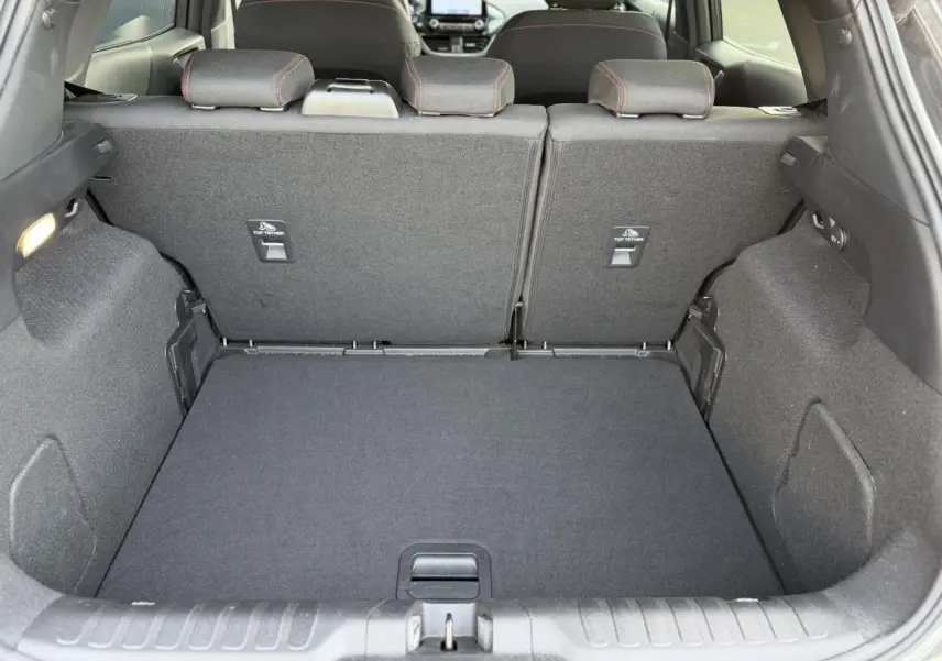 Vue intérieure du coffre arrière du Ford Puma 2024 gris magnétique, montrant les dossiers de sièges arrière et le plancher plat.