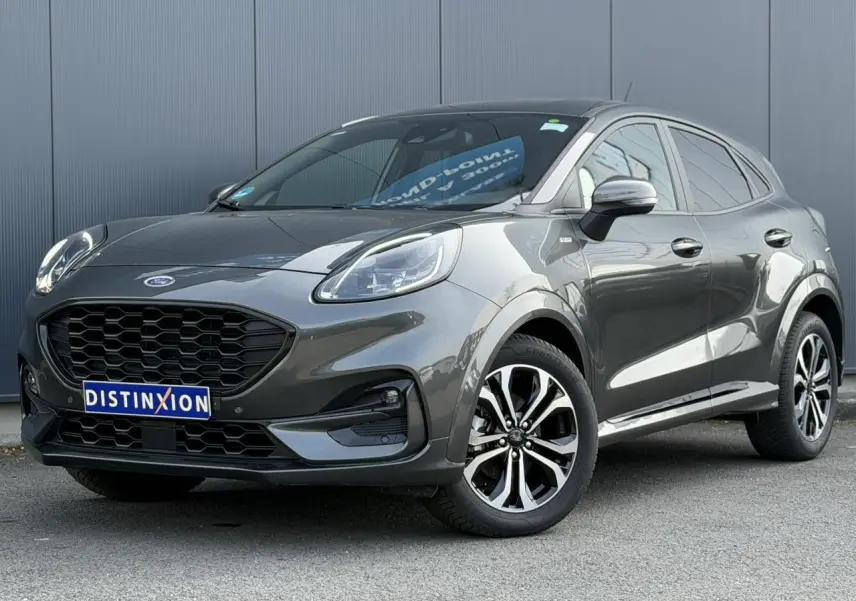Ford Puma Ecoboost gris magnétique en 3/4 avant droit, avec calandre noire et jantes alliage diamantées 17 pouces.