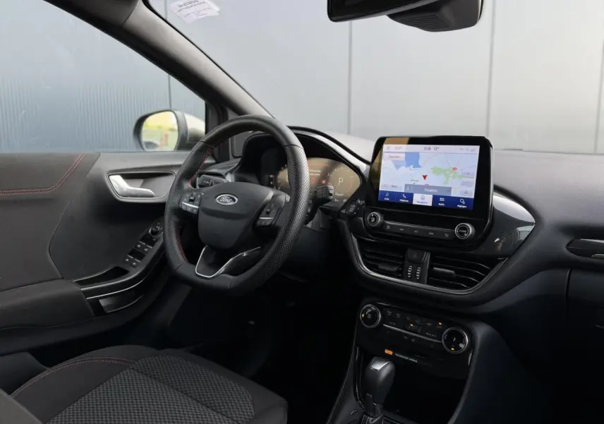 Vue intérieure côté conducteur du Ford Puma gris magnétique 2024, avec tableau de bord numérique et écran tactile GPS.