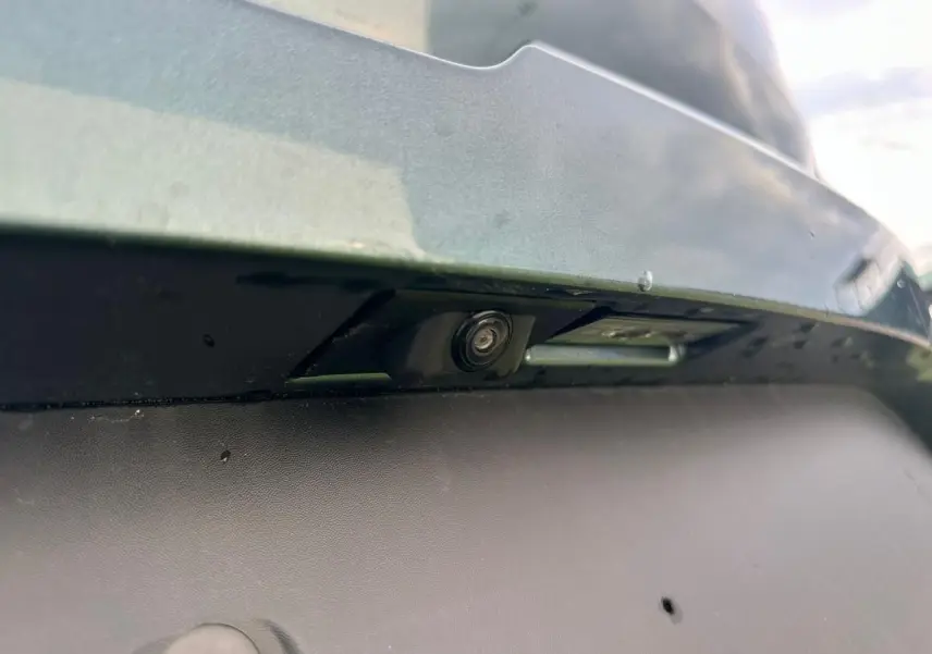 Gros plan sur la caméra de recul sous le pare-chocs arrière du Dacia Sandero III Stepway Vert Cèdre.