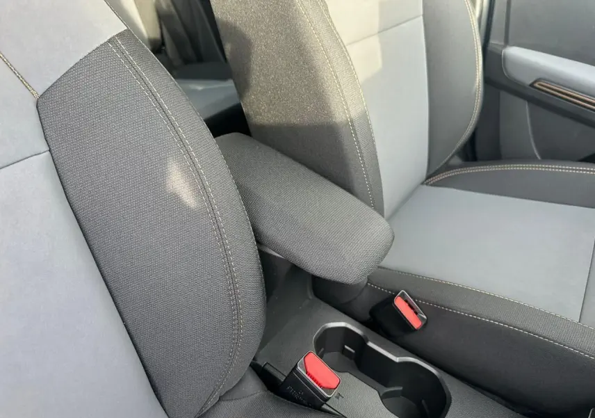 Gros plan sur l'accoudoir central et les sièges avant gris avec surpiqûres contrastantes de la Dacia Sandero III Stepway.
