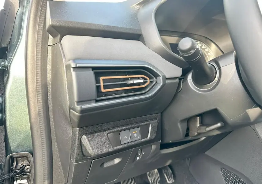 Détail intérieur côté gauche avec sortie d’air brun cuivré et bouton de gestion GPL sur Dacia Sandero Vert Cèdre 2025.