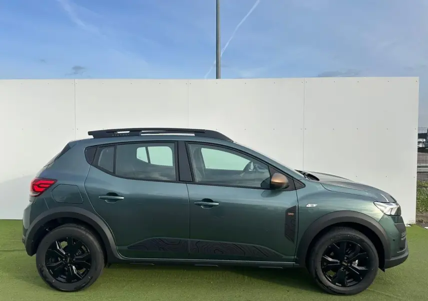 Profil droit de la Dacia Sandero III Stepway 2025 en Vert Cèdre avec jantes noires et barres de toit brun cuivré.