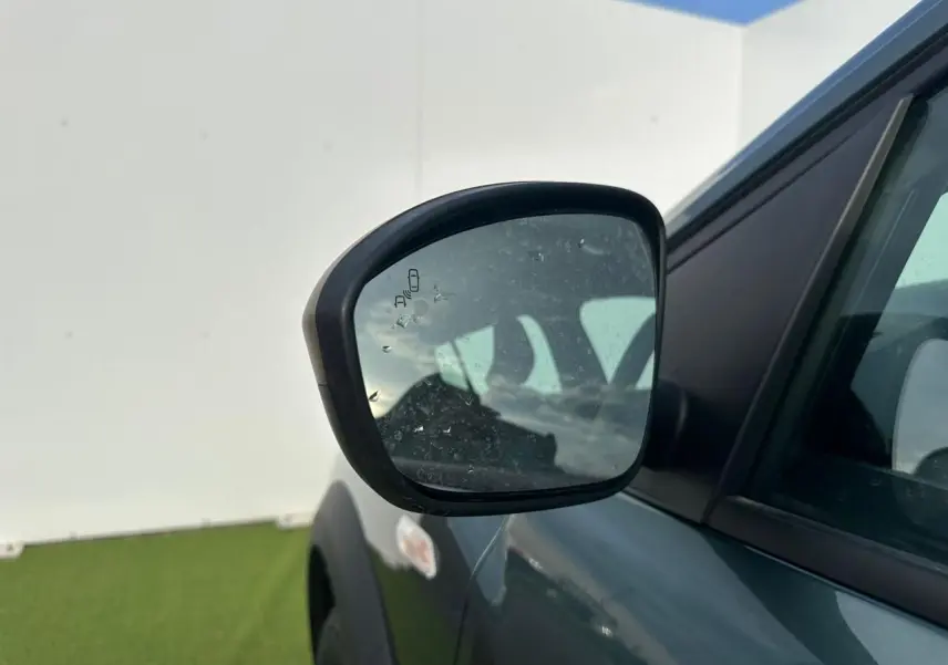 Rétroviseur droit de la Dacia Sandero III Stepway vert cèdre, avec capteur d’angle mort visible sur le miroir.