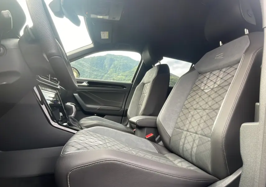 Vue intérieure côté droit montrant les sièges avant en tissu et cuir gris avec surpiqûres et accoudoir central du Volkswagen T-Roc.