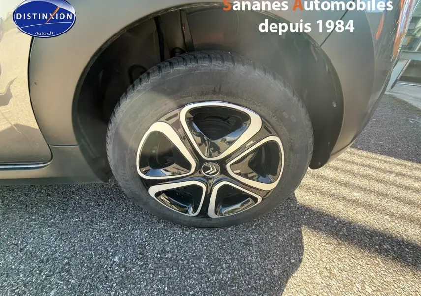 Gros plan sur la roue avant droite d'une Citroën C3 gris foncé avec jante noire et argentée distinctive.