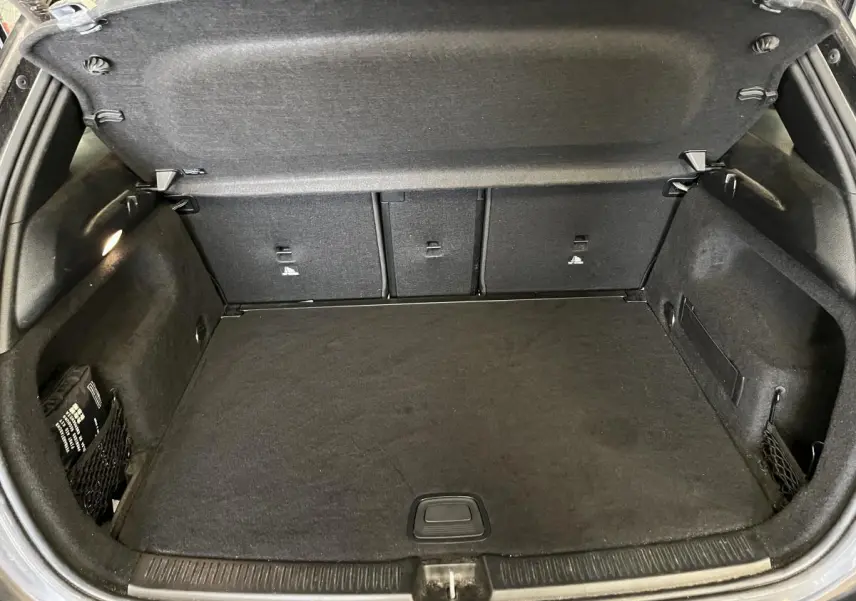 Coffre ouvert noir du Mercedes Classe B 180 d 2019, vue intérieure arrière montrant le plancher et les rangements latéraux.