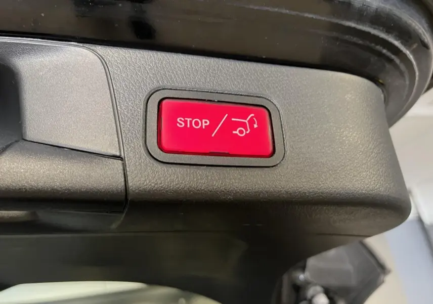 Bouton rouge d'arrêt électrique du hayon sur le coffre noir d'une Mercedes Classe B 180 d 2019 vue en gros plan.