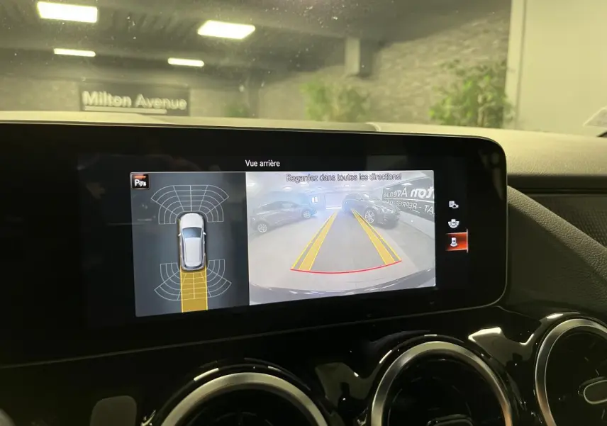 Écran central tactile montrant la caméra de recul et l’aide au stationnement d’une Mercedes Classe B noire de 2019.