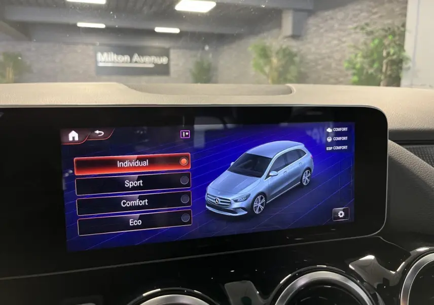 Écran tactile central affichant les modes de conduite avec une illustration 3D argentée de la Mercedes Classe B.