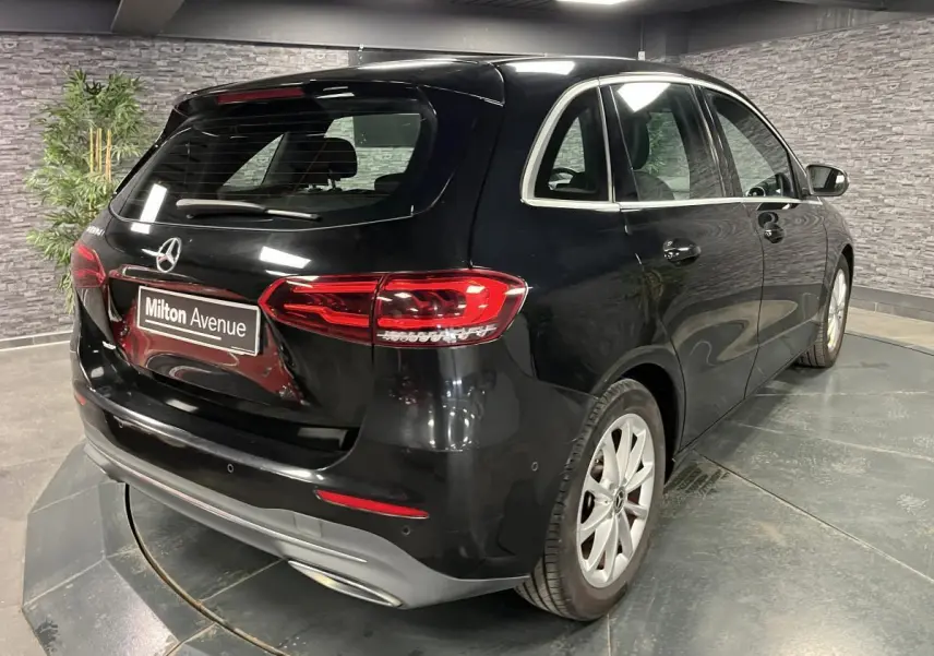 Vue 3/4 arrière droite d'une Mercedes Classe B noire avec feux LED et jantes alliage 17 pouces dans un showroom.