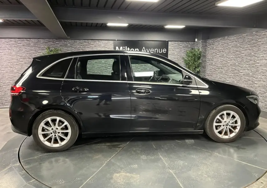 Mercedes Classe B 180 d noire vue de profil côté gauche, avec jantes alliage argent et poignées chromées.