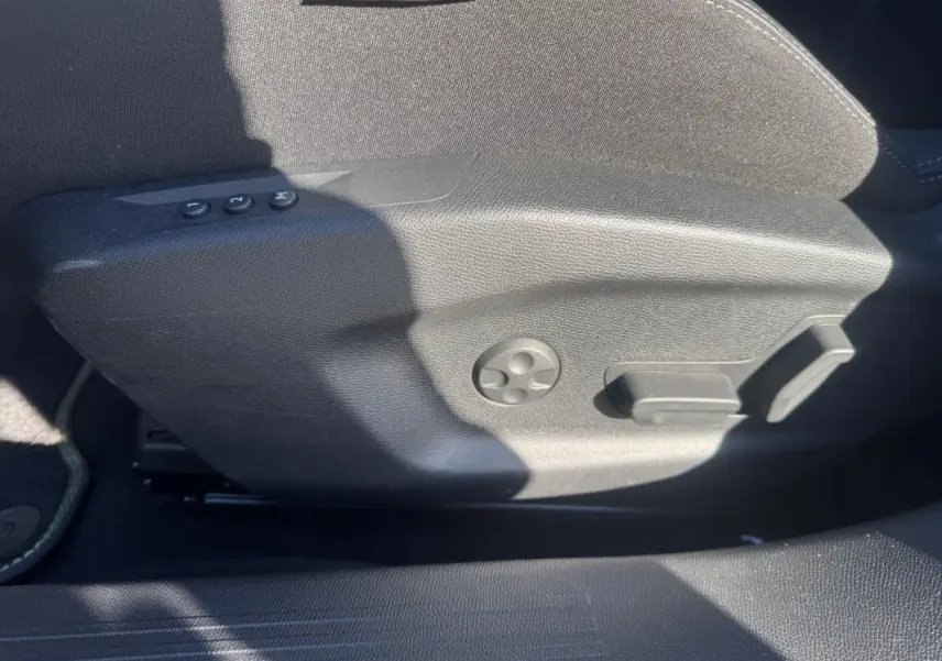 Vue rapprochée du côté gauche du siège conducteur gris avec commandes de réglage électrique et mémoire sur Peugeot 408 Hybrid 2024.