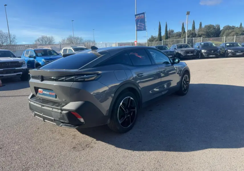 Peugeot 408 gris en 3/4 arrière droit, avec jantes alliage noires et vitres teintées, stationnée en extérieur.