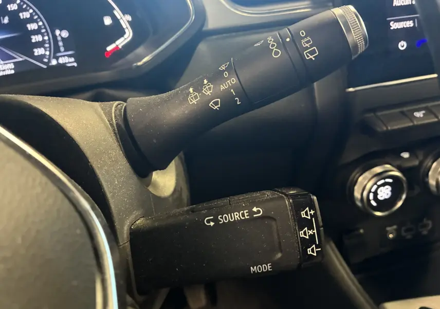 Gros plan sur les commandes au volant du Renault Captur bleu 2021, avec levier d’essuie-glace et commande multimédia.