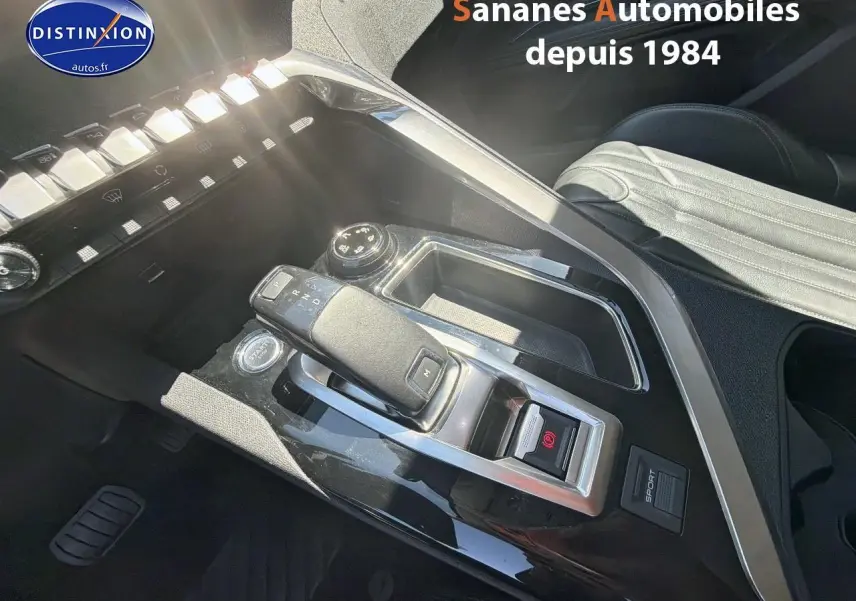 Gros plan sur la console centrale noire avec levier de vitesse et bouton start du Peugeot 3008 blanc, intérieur cuir clair.