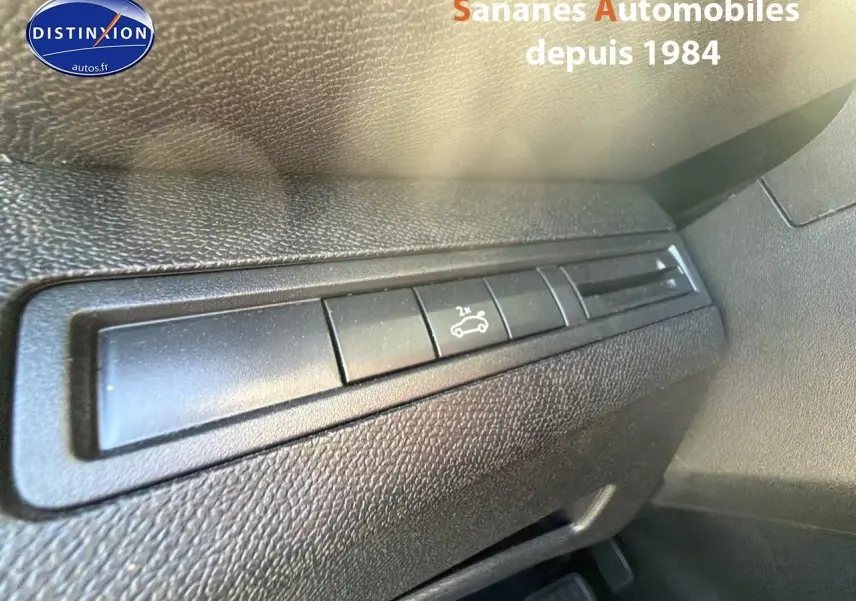 Détail du bouton d'ouverture du hayon sur le tableau de bord intérieur d'un Peugeot 3008 blanc.
