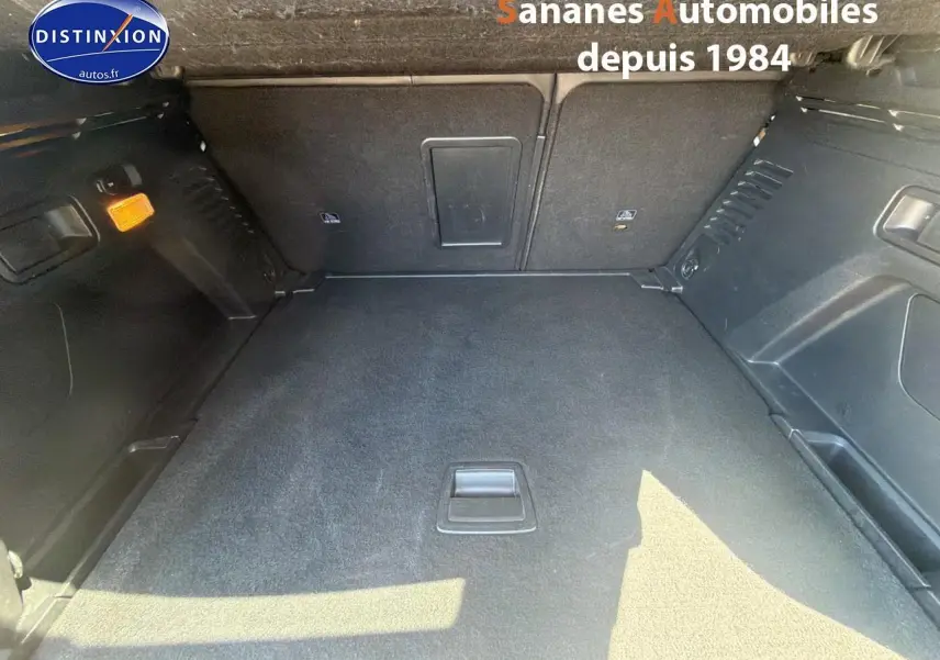 Coffre spacieux et vide du Peugeot 3008 blanc, vue intérieure depuis l'arrière avec revêtement noir et éclairage ambiant.