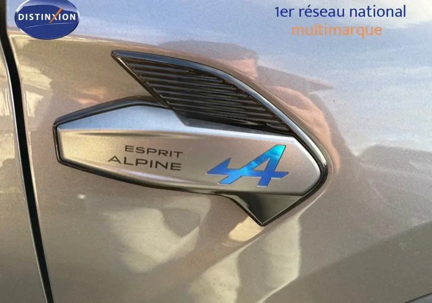 Détail de l'emblème Esprit Alpine bleu sur la portière côté gauche d'une Renault Symbioz gris Cassiope 2024.